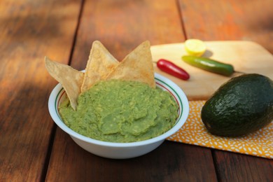 Photo of Delicious guacamole made of avocados with nachos on wooden table