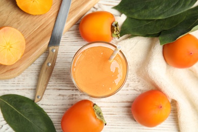 Photo of Tasty persimmon smoothie and fresh fruits on white wooden table, flat lay