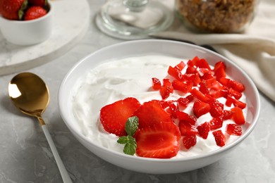 Photo of Delicious yogurt served with strawberries on grey marble table, closeup