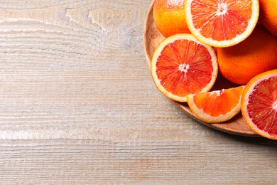 Photo of Whole and cut red oranges on wooden table, above view. Space for text