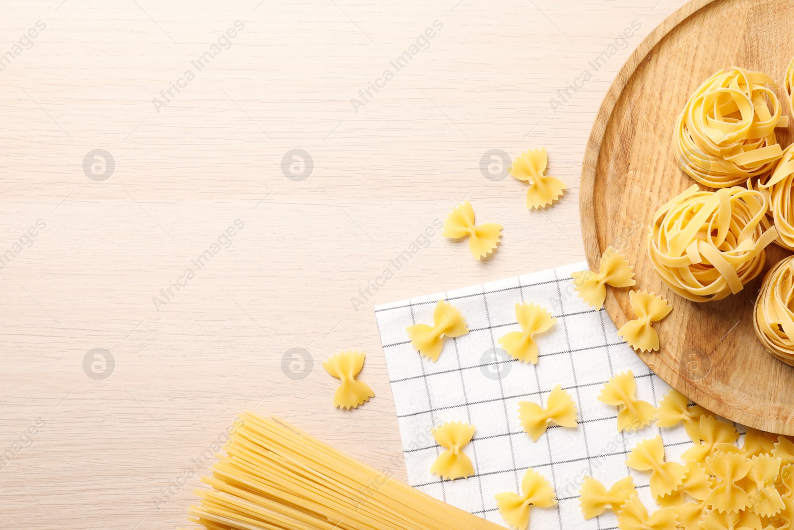 Photo of Different types of pasta on white wooden table, flat lay. Space for text