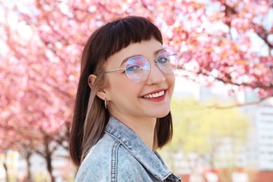 Photo of Beautiful young woman near blossoming sakura trees in park