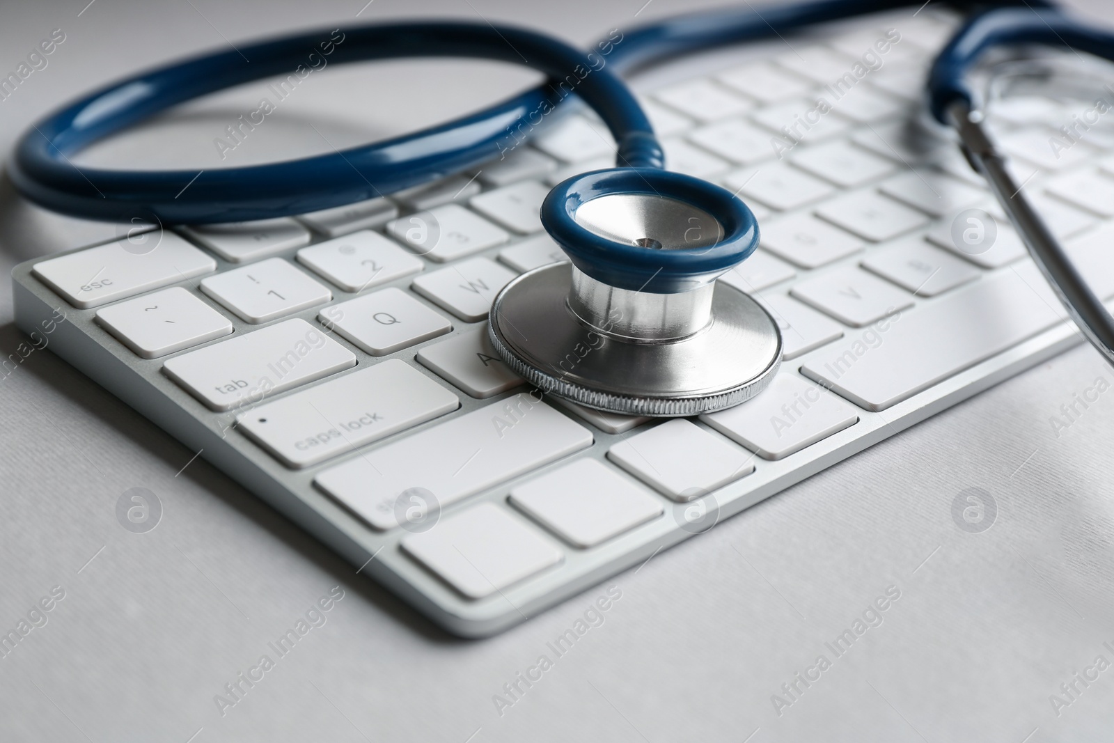 Photo of Keyboard and stethoscope on light grey table, closeup. Concept of technical support