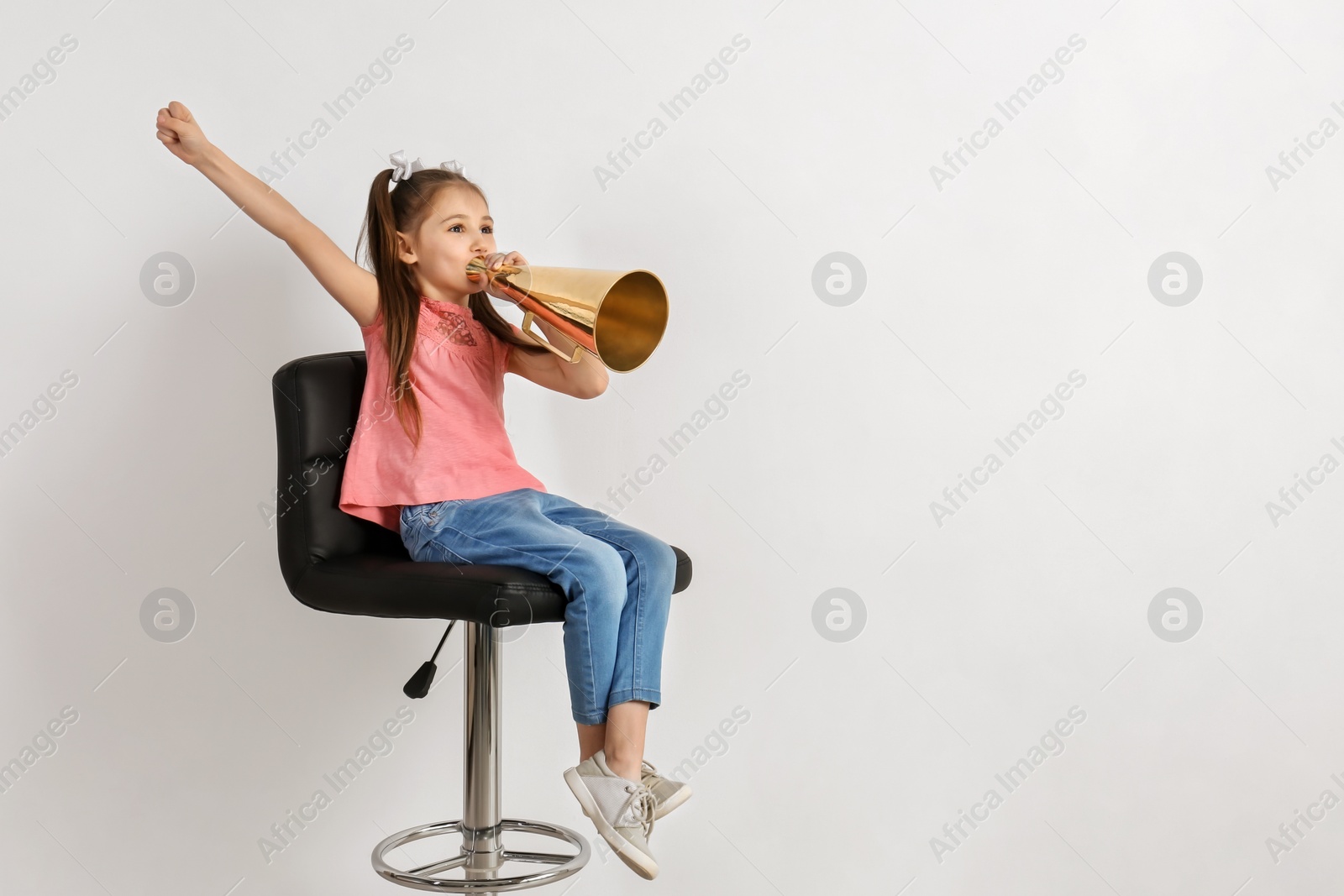 Photo of Cute little girl with megaphone sitting against white background