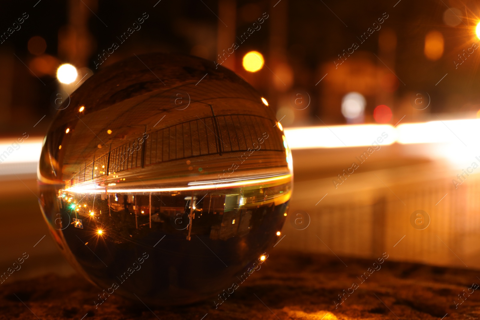 Photo of Beautiful city street, overturned reflection. Crystal ball at night, closeup. Space for text