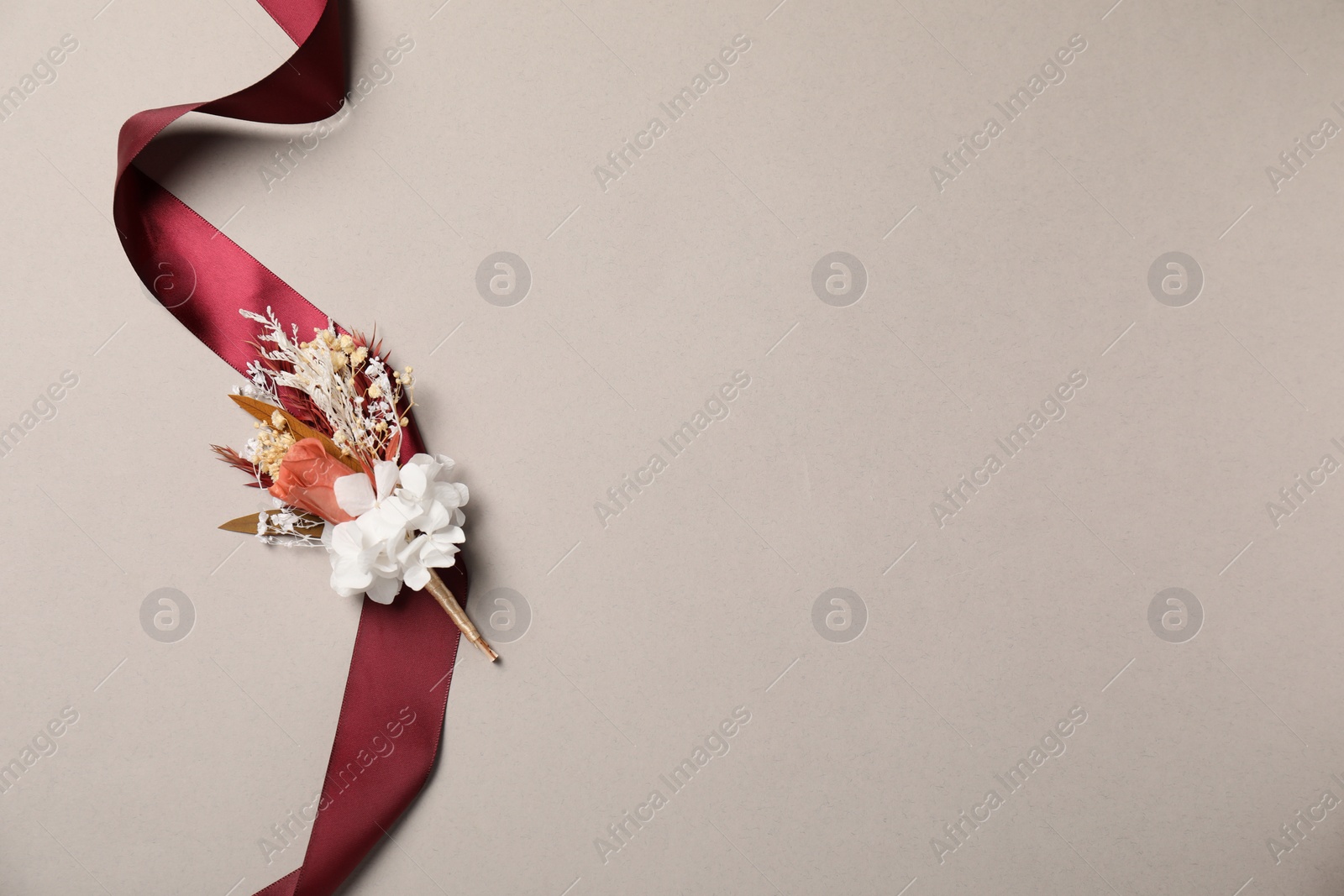 Photo of Stylish boutonniere and red ribbon on light grey background, top view. Space for text