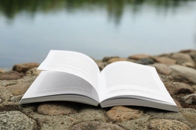 Photo of Open book on rocky shore near river