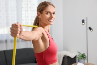 Photo of Athletic woman doing exercise with fitness elastic band at home