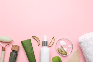 Photo of Cosmetic products, cut aloe leaves and face roller on pink background, flat lay. Space for text