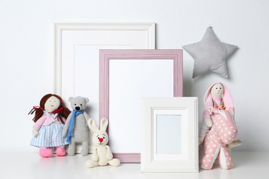Photo of Soft toys and photo frames on table against white background, space for text. Child room interior