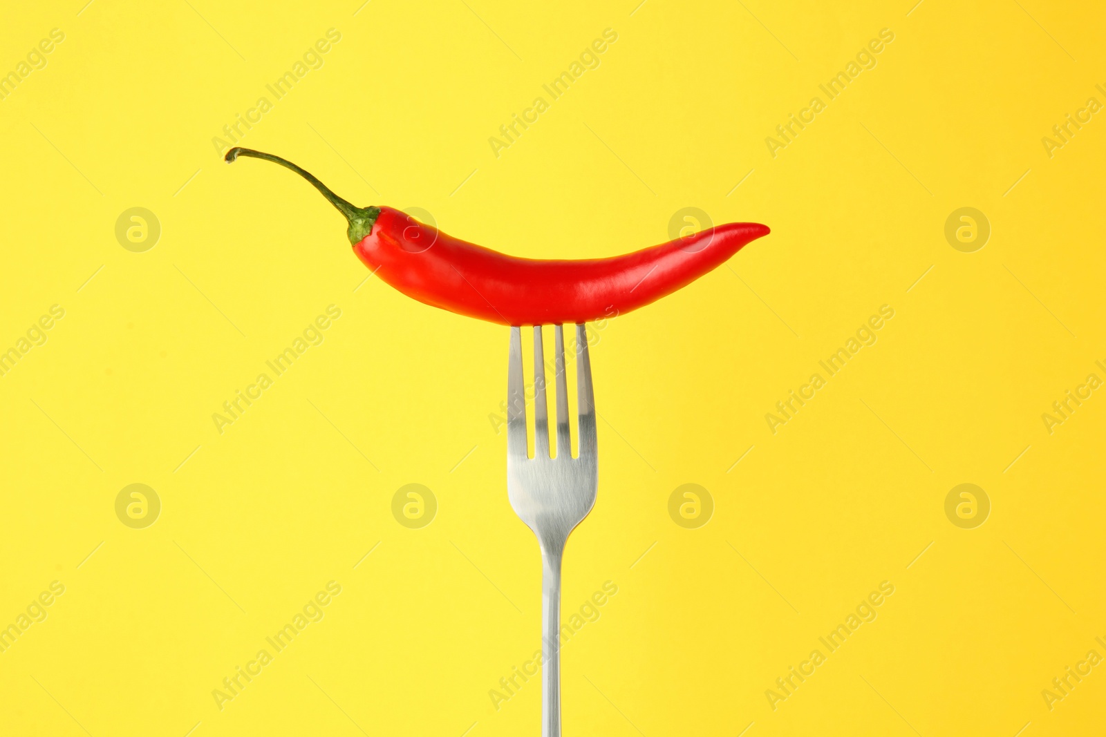 Photo of Fork with chili pepper on yellow background
