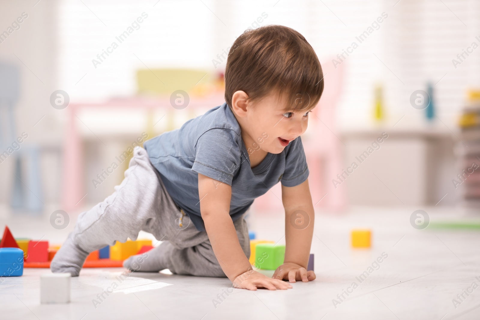 Photo of Cute little child playing with toys on floor at home