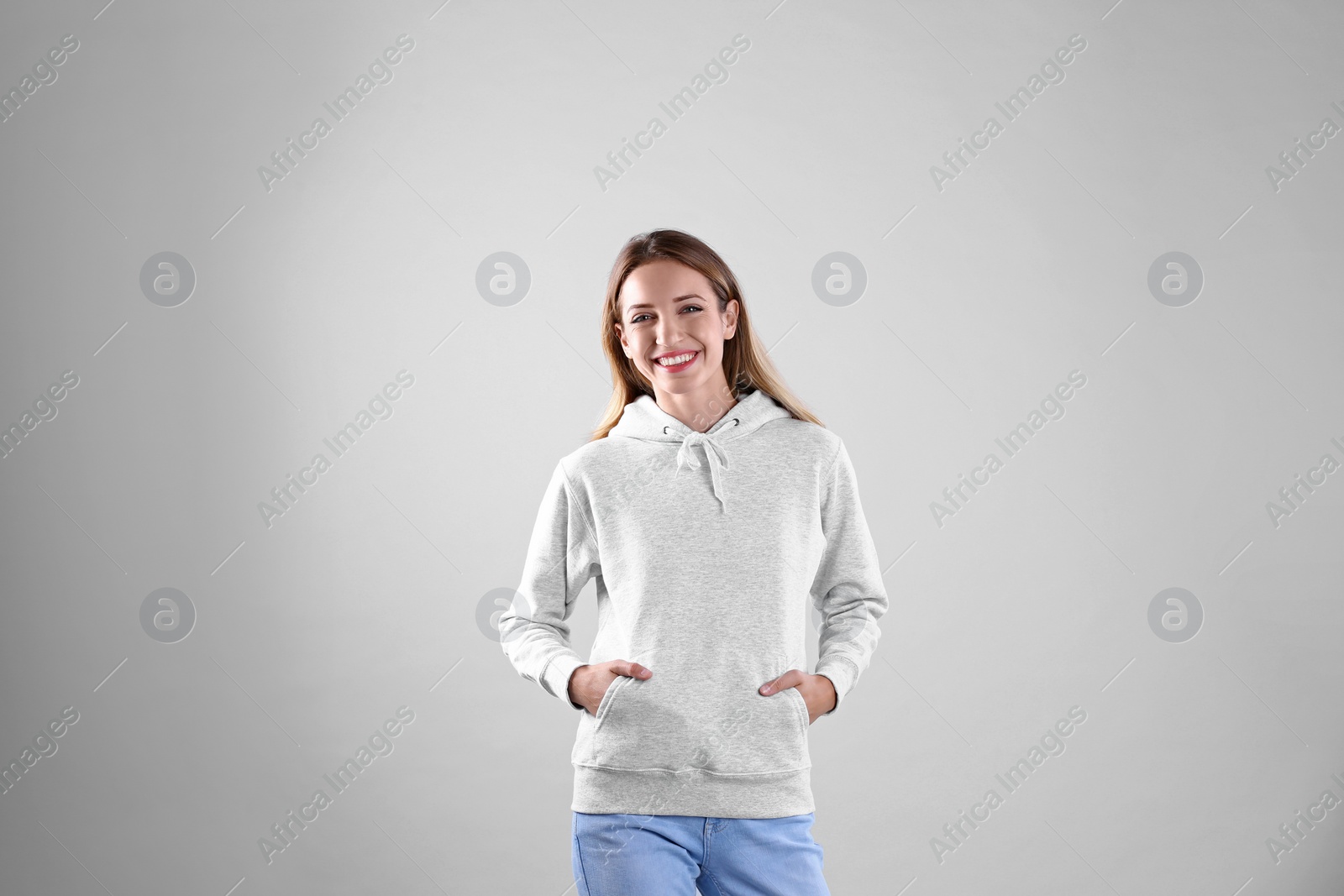 Photo of Portrait of woman in hoodie sweater on light background. Space for design