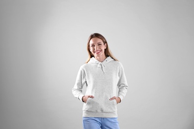 Portrait of woman in hoodie sweater on light background. Space for design