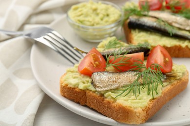 Photo of Delicious sandwiches with sprats, tomatoes, dill and avocado puree served on white table, closeup