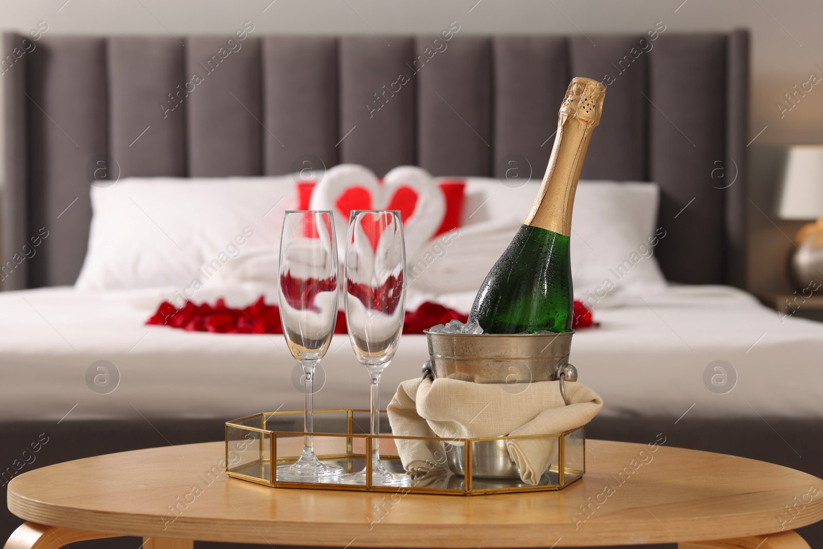 Photo of Honeymoon. Sparkling wine and glasses on wooden table in room