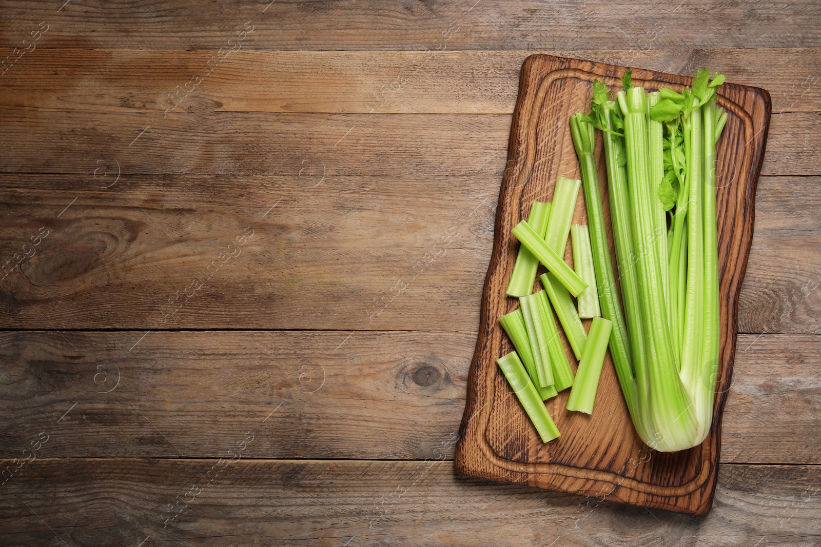 Photo of Fresh green celery on wooden table, top view. Space for text