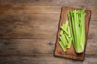 Photo of Fresh green celery on wooden table, top view. Space for text