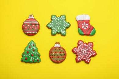 Different tasty Christmas cookies on yellow background, flat lay