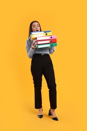 Stressful woman with folders on orange background