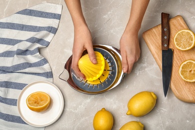 Photo of Woman squeezing lemon with juicer on table, top view