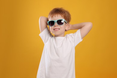 Photo of Cute little boy with sunglasses on yellow background