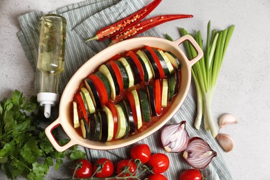 Cooking delicious ratatouille. Dish with different cut vegetables on light grey table, flat lay