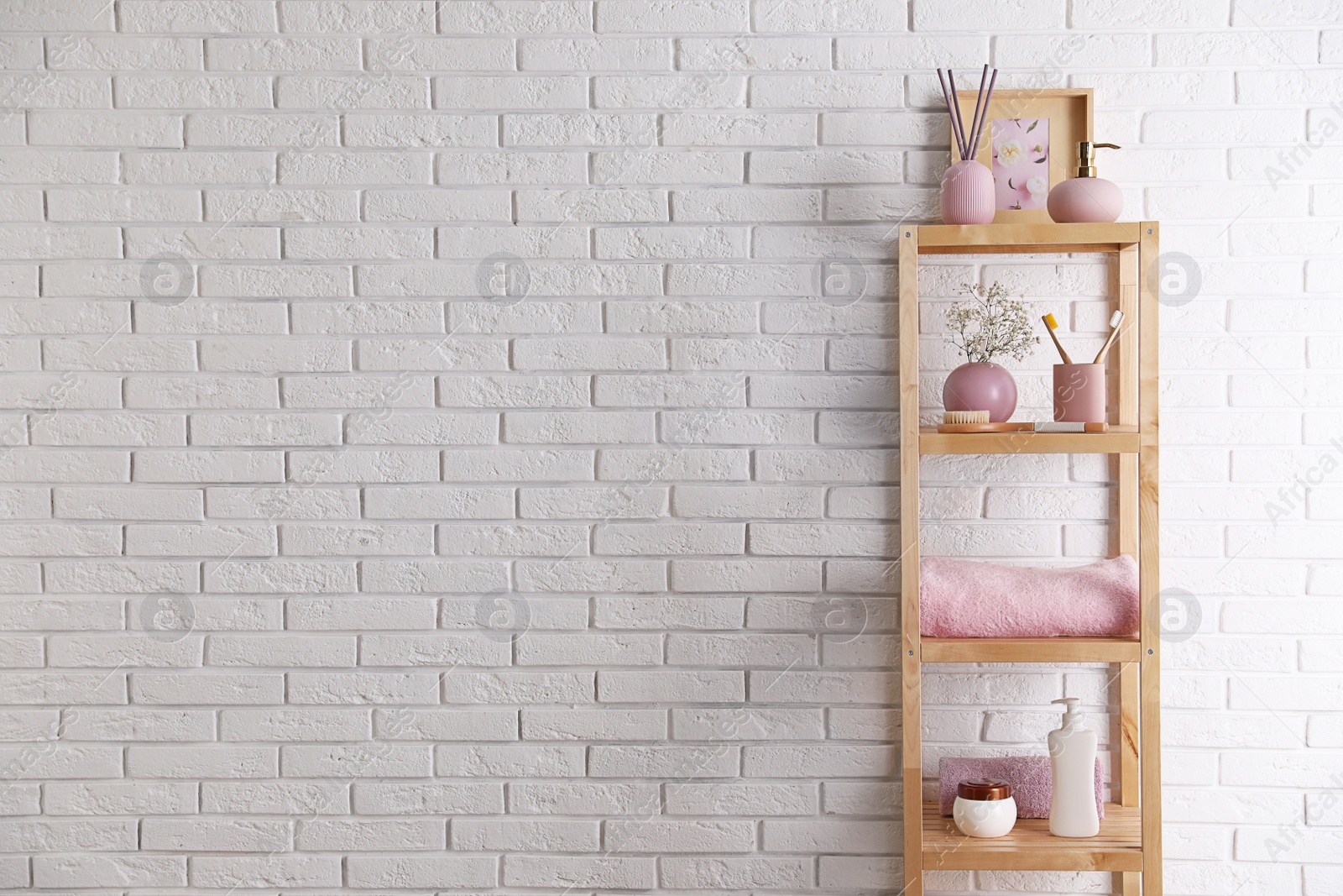 Photo of Shelving unit with toiletries near white brick wall indoors, space for text. Bathroom interior element