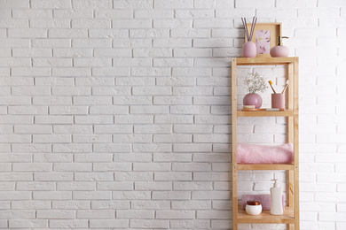 Photo of Shelving unit with toiletries near white brick wall indoors, space for text. Bathroom interior element