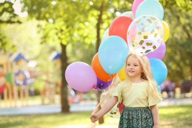 Photo of Cute girl with colorful balloons in park on sunny day