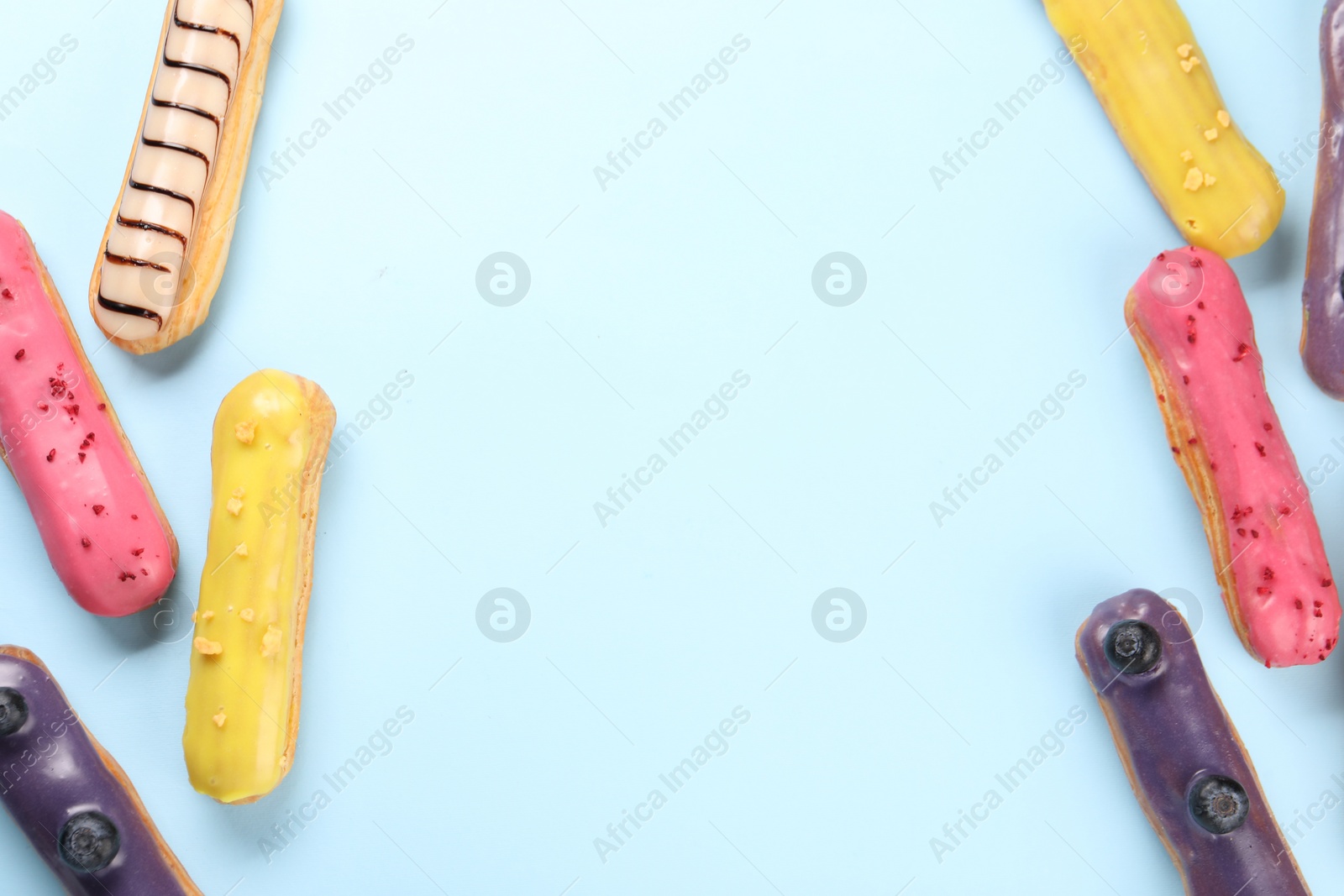 Photo of Delicious eclairs covered with glaze on light blue background, top view. Space for text