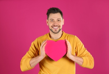 Portrait of handsome man with decorative heart on color background