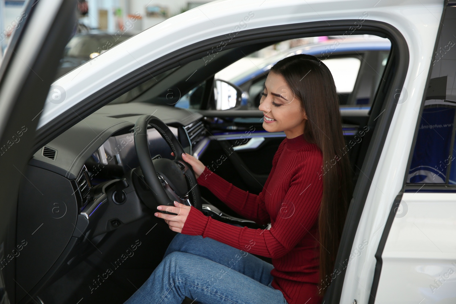 Photo of Young woman sitting in car at dealership