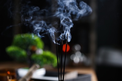 Incense sticks smoldering on blurred background, closeup
