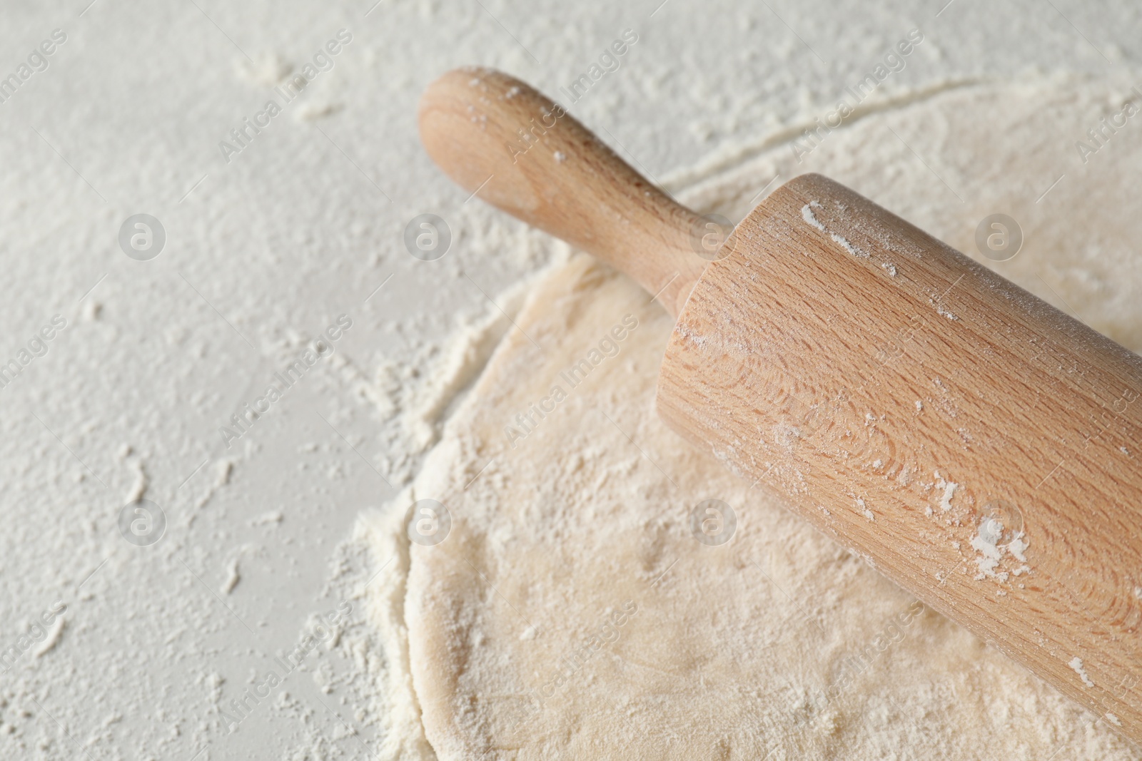 Photo of Raw dough and rolling pin on table, space for text