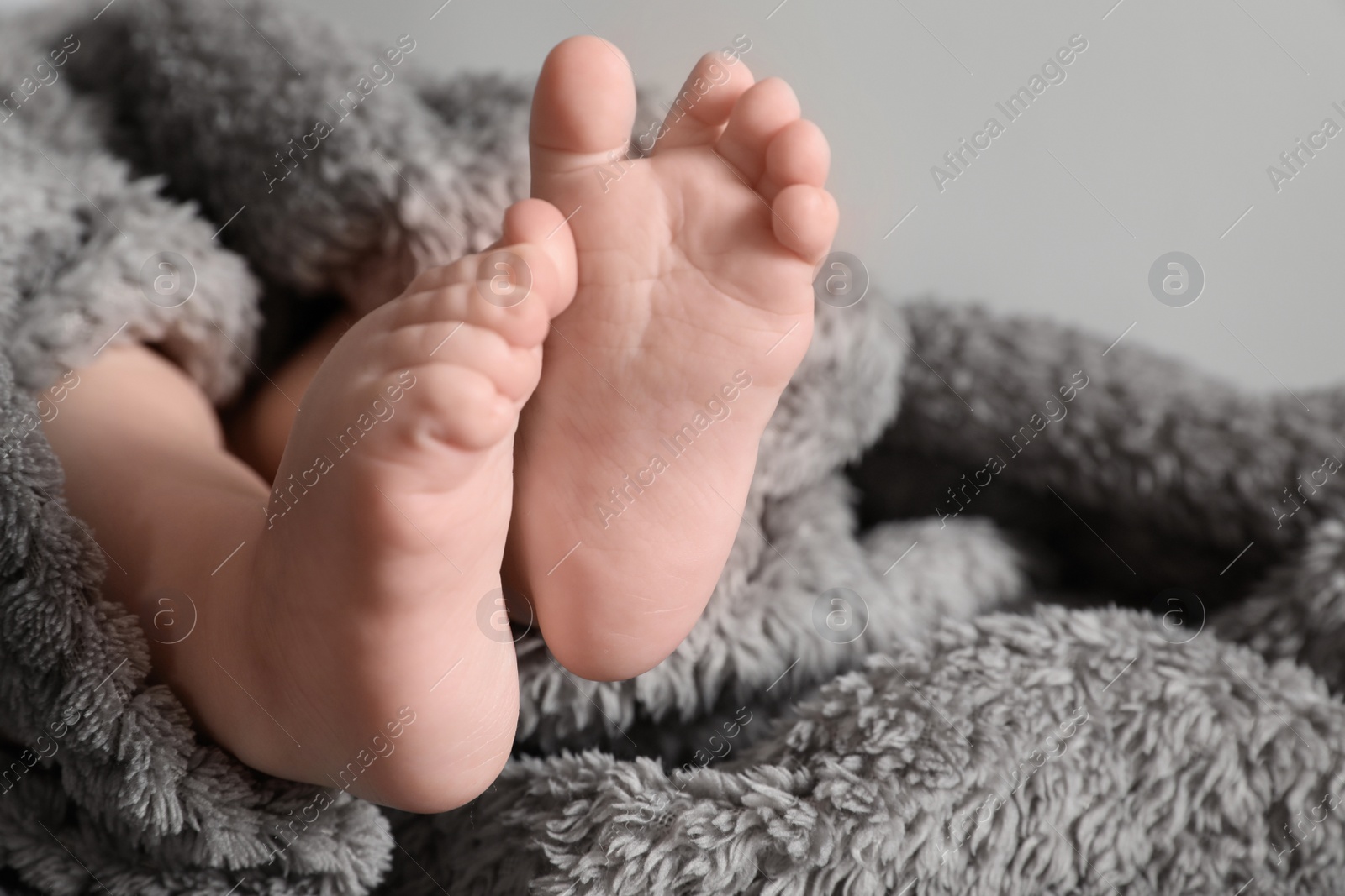 Photo of Little baby with cute feet on soft blanket, closeup. Space for text