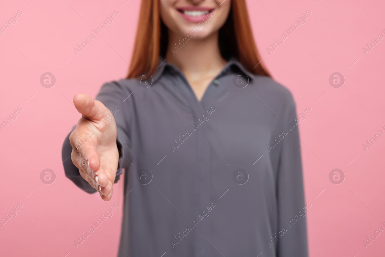 Photo of Woman welcoming and offering handshake on pink background, closeup