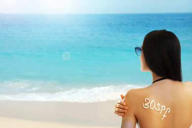Image of Young woman with sun protection cream on her back at beach
