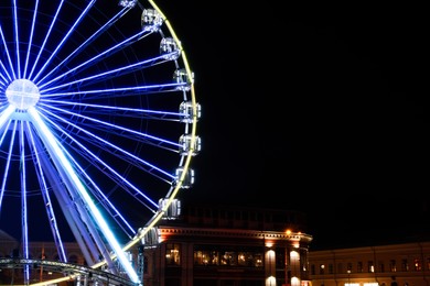 Photo of Beautiful glowing Ferris wheel in city at night. Space for text
