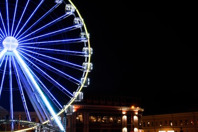 Beautiful glowing Ferris wheel in city at night. Space for text