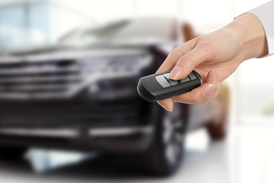 Image of Woman with key near new automobile indoors, closeup