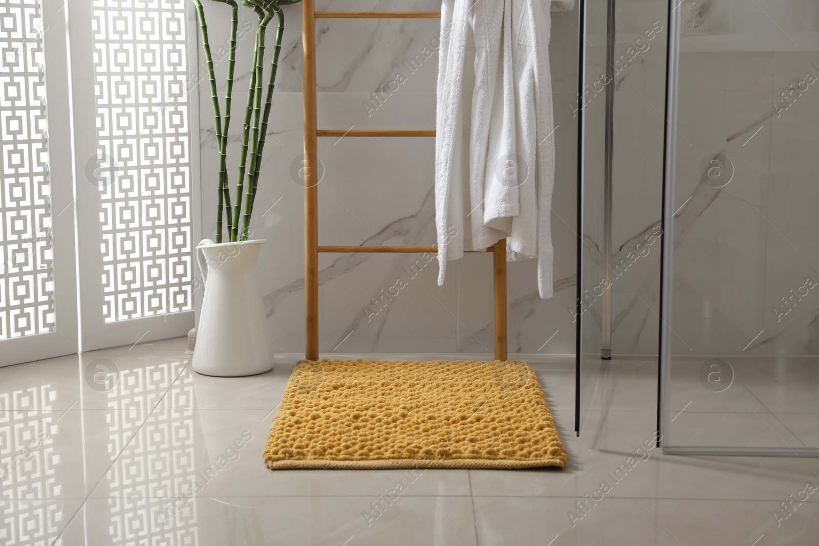 Photo of Soft orange bath mat on floor in bathroom