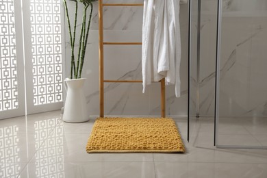 Photo of Soft orange bath mat on floor in bathroom