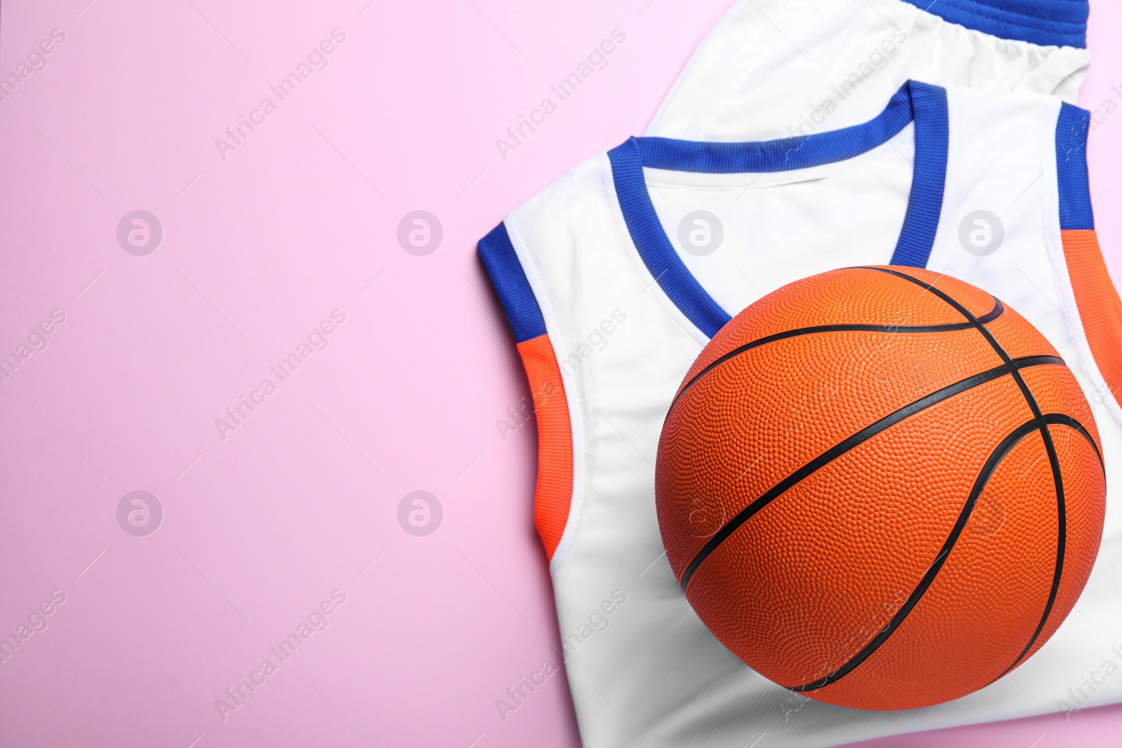 Photo of Basketball uniform and ball on pink background, top view. Space for text