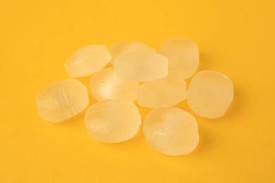 Photo of Many cough drops on orange background, closeup