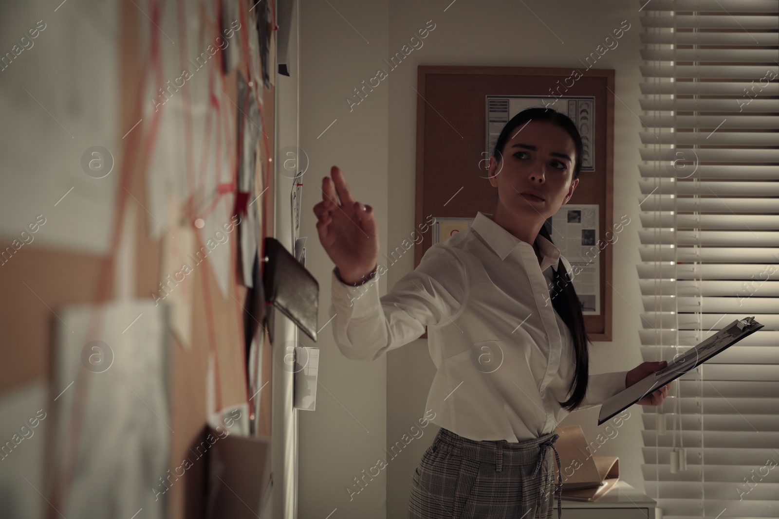 Photo of Detective looking at evidence board in office