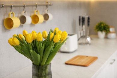 Spring interior. Bouquet of beautiful yellow tulips on white countertop in stylish kitchen, space for text