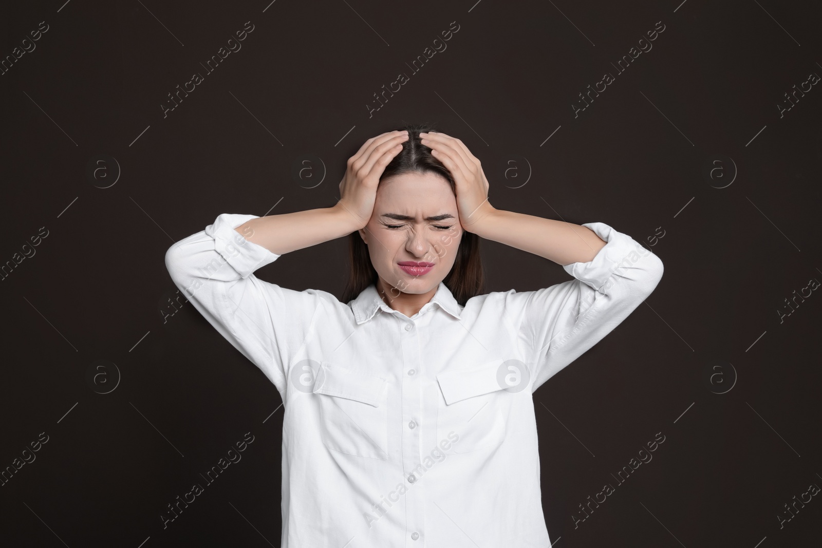 Photo of Young woman suffering from headache on brown background