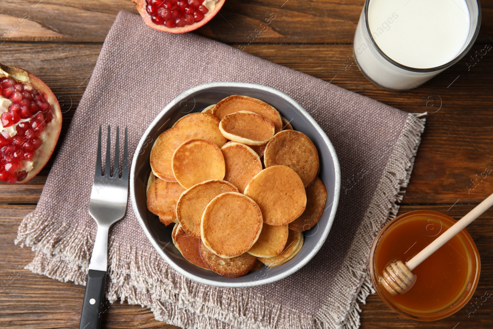 Photo of Delicious mini pancakes cereal served on wooden table, flat lay