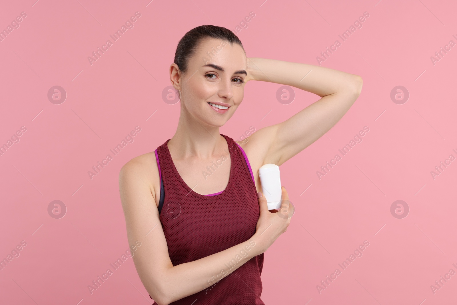 Photo of Beautiful woman applying deodorant on pink background